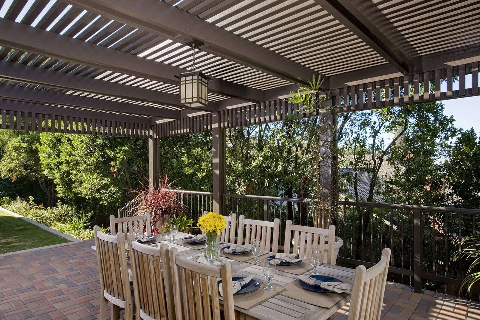 A wooden pergola covers an outdoor dining area.